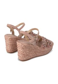 Sandali zeppa beige con cinture incrociate, arricchiti da perline e pietre. La zeppa presenta una texture intrecciata, offrendo una base stabile.
