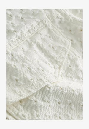 Weißer Stoff mit strukturiertem Muster, das kleine erhabene Punkte und ein weiches, leicht unregelmäßiges Gewebe aufweist. Glatte Kanten und Nähte sind sichtbar.