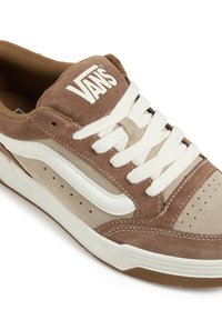 Brown suede sneaker with cream accents, textured surface, white laces, and Vans logo on the tongue. Detailed stitching and perforated sides.