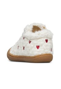Scarpina bianca pelosa per bambino con motivi a cuore rossi e suola marrone flessibile, mostrata da un angolo posteriore.