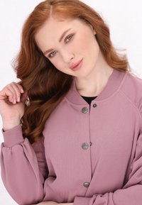 Sweatshirt rosa chiaro con scollatura rotonda, maniche raglan e bottoni argento. Tessuto morbido e vestibilità comoda.