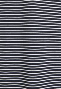 Gros plan sur un tissu lisse avec des rayures horizontales blanches et bleu marine foncé espacées de manière égale.
