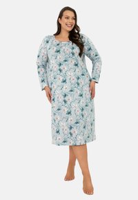 Kwiatowa koszula nocna w jasnoniebieskim kolorze, z długimi rękawami, falbaniastym dekoltem oraz lekkim materiałem z białymi i zielonymi wzorami kwiatowymi.