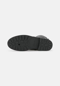 Semelle en caoutchouc noir avec un motif de traction texturé, comportant plusieurs éléments de grip et le logo "Clarks" près du talon.
