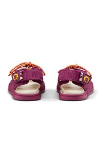 Purple sandals with a textured fabric upper, open back design, contrasting orange laces, and a notable logo patch on the side.