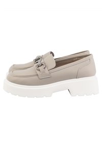 Mocassins en cuir beige avec semelles épaisses blanches à plateforme et détails de boucle chaîne argentée sur le dessus.