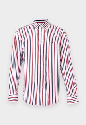 Chemise blanche boutonnée avec des rayures verticales rouges et bleu marine, col boutonné et petit logo sur la poitrine, présentée sur un fond neutre.