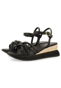 Sandalias de cuero negras con tiras entrelazadas, plataforma con acento de yute trenzado y suela de goma texturizada con un patrón en zigzag.