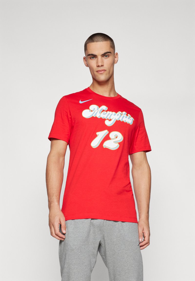 T-shirt en coton rouge avec le texte en blanc en cursive "Memphis" et le numéro "12" en caractères gras et texturés. Col rond ; manches courtes.