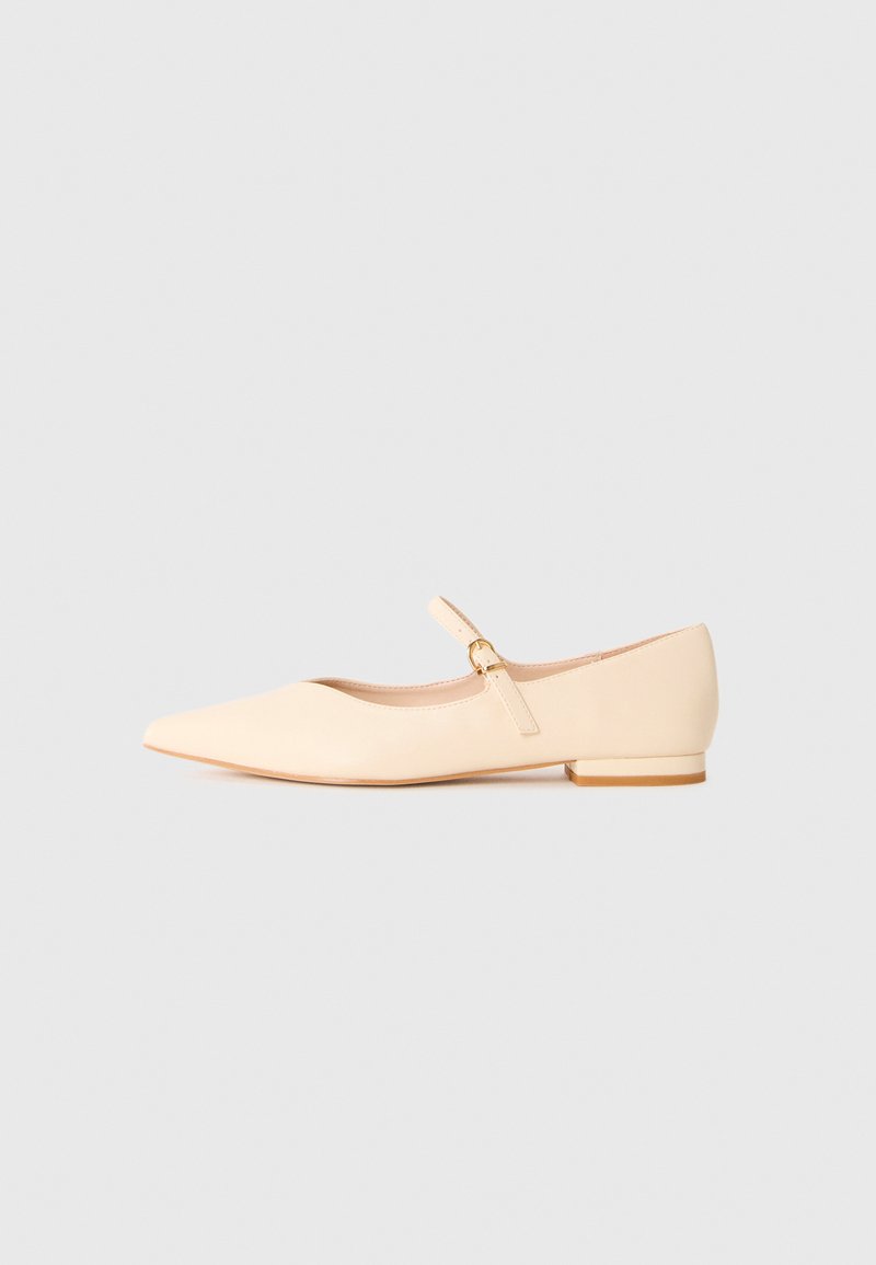 Beige pointed-toe Mary Jane flat shoe with a small heel and a thin strap fastened by a gold buckle on a white background.