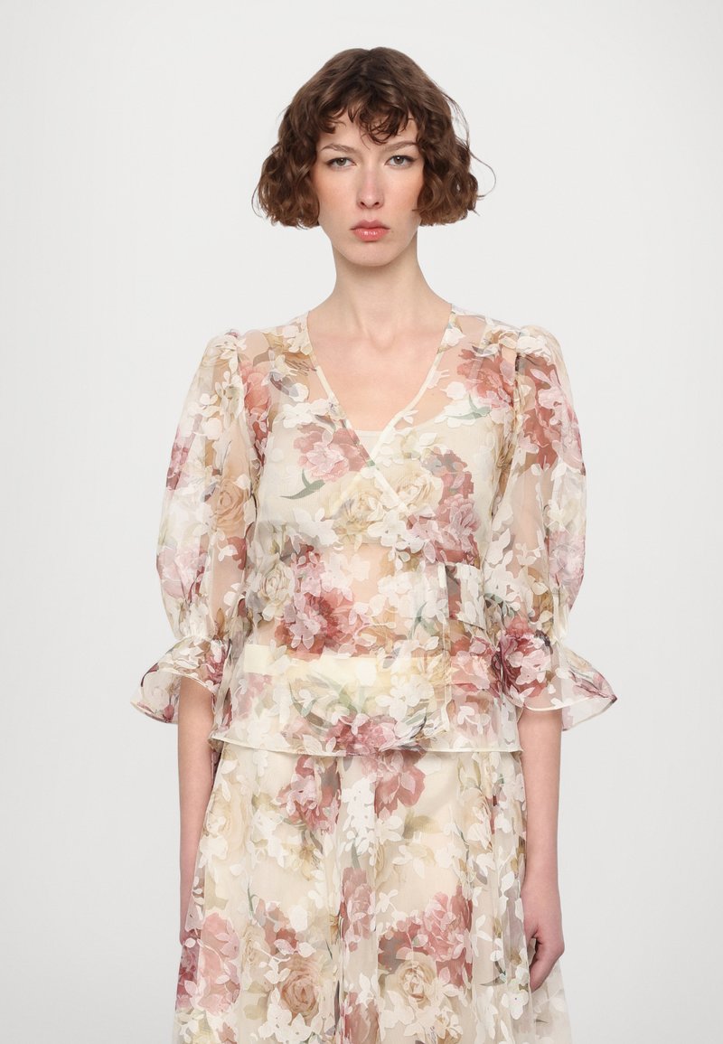 Doorzichtige bloes met bloemenprint met roze en crèmekleurige rozen, V-hals, pofmouwen en gelaagde ruffles aan de onderkant, met een lichte, transparante textuur.