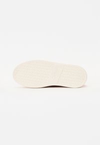 Semelle de chaussure en caoutchouc blanche avec motifs circulaires et "Gabor" embossé au centre.