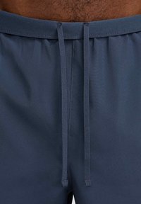 Marina simshorts med dragsko i midjan, slät textur och elastisk midjeresår. Uppvisar ren sömnad och inga synliga logotyper eller mönster.