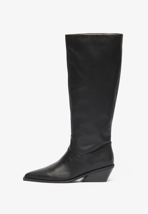 Bottes noires en cuir montantes avec un bout pointu et un talon en forme géométrique. Texture lisse avec un minimum de détails et une silhouette ajustée.
