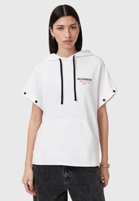 Sudadera blanca con capucha y mangas cortas, con cordones negros y un bolsillo frontal. Incluye bordados y botones decorativos en las mangas.
