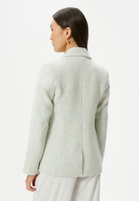 Ljusblå texturerad blazer med skräddarsydd passform, utsvängda slag och detaljer med bakventil. Lämplig för formella tillställningar eller smart casual klädsel.