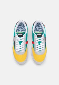 Puma-sneakers i turkos, gult och grått färgschema, med vita snören, texturerad tyg och mönstrad innersula.