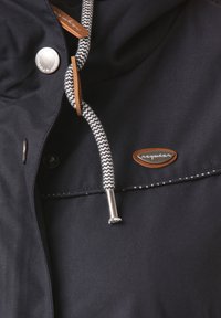 Černá bunda s stříbrným patentním knoflíkem, kontrastní bílou a černou šňůrkou, koženou cedulkou s názvem značky a bílým prošitím jako ozdobou.