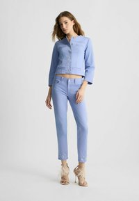 Helle blaue, denimartige Jacke mit cropped Schnitt, langen Ärmeln, verzierten Knöpfen und passenden, schmal geschnittenen Hosen mit Blumen-Applikationen am Saum.