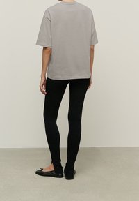 Gray cotton t-shirt with short sleeves and a relaxed fit, paired with black leggings and black flats. Simple and minimalistic design.