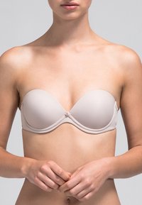 Sostén nude sin tirantes con copas moldeadas y suaves, con un ligero brillo, soporte de aros y un pequeño detalle en el centro. Presenta bordes sin costuras para mayor comodidad.