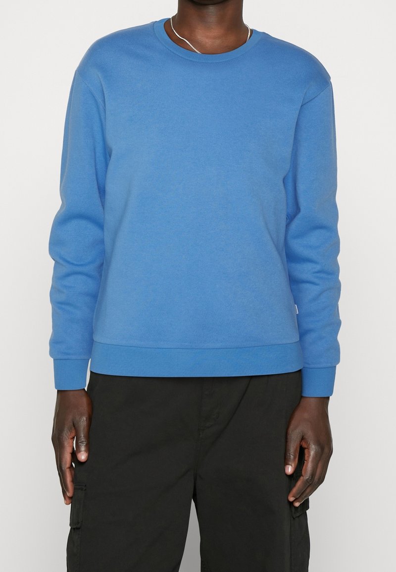 Blå sweatshirt med rund hals, ribbade ärmslut och nederkant. Tillverkad av mjukt, texturerat tyg, har den en avslappnad passform och minimalistisk design.