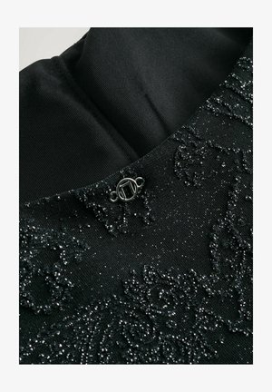 Fekete textília, ami textúrált felszínű, bonyolult gyöngyös mintákkal. Kicsi, kör alakú fém csattal rendelkezik a nyakrésznél.