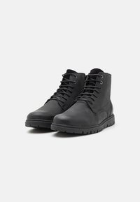 Botas de tobillo de cuero negro con un acabado suave, punta redondeada y diseño de cordones. Cuenta con una suela de goma texturizada para mayor agarre.
