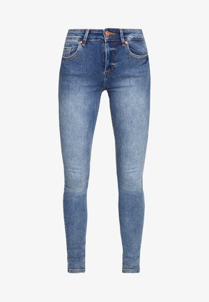 Jean skinny bleu délavé avec une taille mi-haute, cinq poches, bouton avant et passants de ceinture, présenté sur fond blanc.