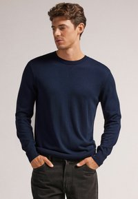 Dunkelblauer Rundhals-Pullover aus weichem Material, mit langen Ärmeln und gerippten Bündchen und Saum für eine figurbetonte Passform.