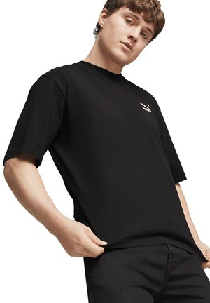Zwarte kortebloed t-shirt van katoen, met een subtiel wit logo op de borst. De stof ziet er glad uit met een losse pasvorm.