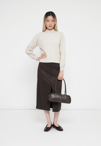 Kreemi ribbed knit neule, tumma ruskea midi-hame, jossa on etureikä, musta nahkakäsilaukku ja kiiltävät burgundinpunaiset ballerinat.