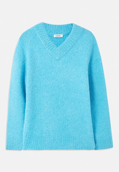 Φωτεινό μπλε, αφράτο πουλόβερ με V-λαιμό, μακριά μανίκια και ριμπ μανσέτες. Φτιαγμένο από μαλακό υλικό, διαθέτει χαλαρή εφαρμογή. Η ετικέτα αναγράφει "SANDRO."
