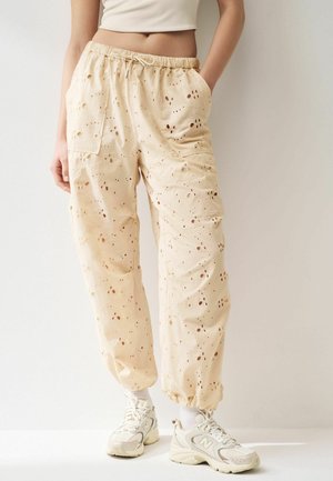 Ljusbeige bomullscargo byxor med broderi och utskurna mönster, med elastisk midja, sidofickor och elastiska muddar.