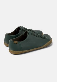 Green leather shoes with a smooth texture, rounded toe, lace-up design, and contrasting gum rubber sole, featuring subtle branding on the heel.