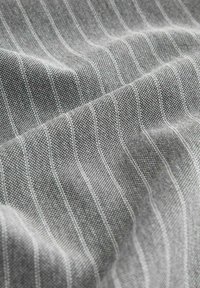 Grijze textuurstof met fijne, verticale witte strepen, die een geweven patroon toont, zachte oppervlakte en visuele diepte.