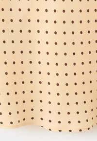 Tissu beige avec de petits pois brun foncé espacés régulièrement formant un motif en grille régulière.