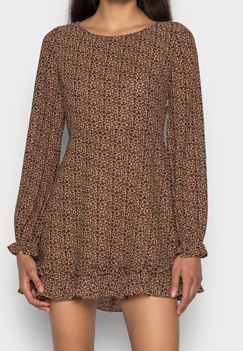 Robe imprimée léopard marron avec manches longues, encolure ronde et ourlet évasé à volants. Réalisée en tissu léger et texturé.
