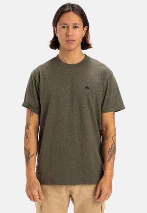 Camiseta de algodón verde oliva con cuello redondo, mangas cortas enrolladas y un pequeño logo negro en el lado izquierdo del pecho.