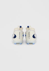 Une paire de crampons de football Nike Phantom off-white avec des accents et des crampons bleus, vue de l'arrière sur un fond blanc uni.