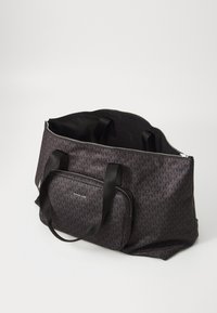 Grand sac fourre-tout noir avec un motif en monogramme, en tissu durable, équipé de poignées doubles et d'une poche avant zippée avec un logo.