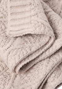 Coperta beige chiaro lavorata a maglia con un motivo testurizzato; presenta punti in rilievo e un aspetto morbido e accogliente. Ideale per tenere caldo.