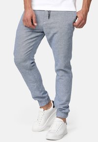 Helle blaue Jogginghosen aus einem weichen Stoff, mit einem Kordelzugbund und gerippten Bündchen, kombiniert mit weißen Turnschuhen.