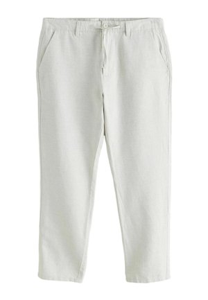 Mand iført lyse beige linnedbukser med et bundet taljebånd og hånden i højre lomme, kombineret med en hvid top.