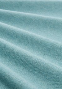 Tessuto azzurro con superficie strutturata, che mostra motivi di tessitura sottili e una morbida drappeggiatura, evidenziando diverse tonalità di blu.