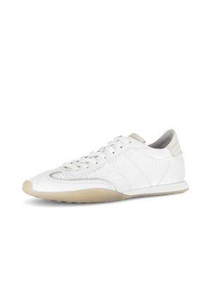 White low-top sneaker with beige sole and accents, featuring laces and textured rubber outsole, shown on a white background.