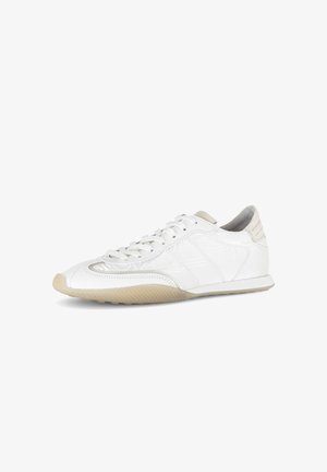 White low-top sneaker with beige sole and accents, featuring laces and textured rubber outsole, shown on a white background.