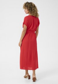 R�öd, knälång klänning i lätt tyg. Korta ärmar, avslappnad passform med midjeband, med en slät, texturerad yta.