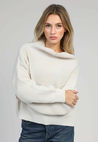 Pull en maille épaisse de couleur beige clair, doté d'un large col montant et de poignets côtelés. La coupe décontractée améliore le confort et le style.