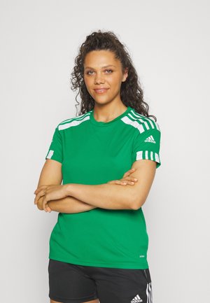 T-shirt de sport verte avec des rayures blanches sur les épaules, à manches courtes et à encolure ronde. Porté avec un short noir présentant un petit logo.